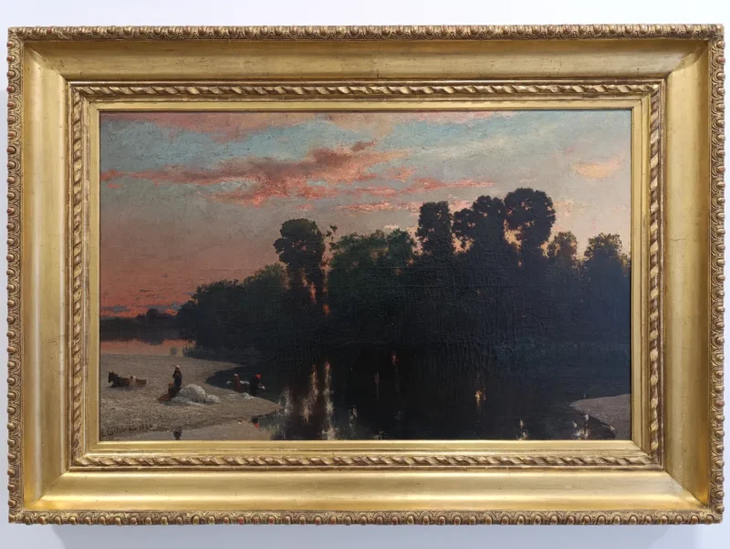 Peinture encadrée représentant un paysage au crépuscule sur les rives du Vidourle : une masse d’arbres sombres borde une étendue d’eau dont la surface reflète le ciel rose et bleu. Sur la gauche, une rive sableuse accueille de petites figures humaines et des animaux près de l’eau. Le ciel occupe la moitié supérieure du tableau, avec des nuages teintés de rose, tandis que la végétation forme une silhouette compacte au centre. Le tout est présenté dans un cadre doré.