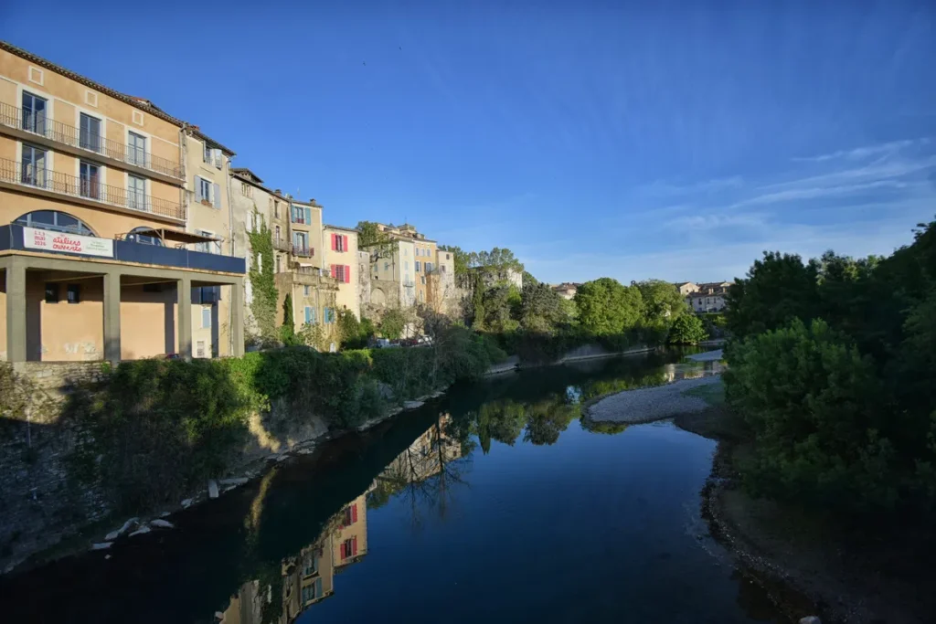 Photo d'un village sous le soleil matinal sur la rive d'un petit fleuve, sous un beau ciel bleu.